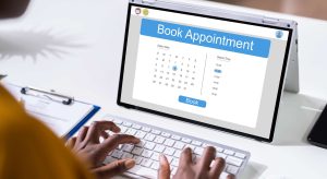 Laptop screen shows an online appointment booking form with a calendar and a 'Book' button, plus time slots on the side.